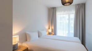 A hotel room with a large bed, a bedside table with a lamp, and a window with curtains. - Pattùs Hôtel (La Grande-Beroche)