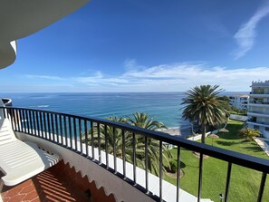 A balcony with a view of the ocean and a building with a pool. - Apartment in Nerja Near Playa El Salon (Nerja)