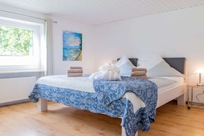 A bedroom with a bed, a painting on the wall, and a window. - Holiday home with 2 bedrooms (Langballig)