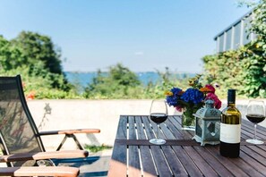 A wooden table with two wine glasses and a bottle, a chair, and a lantern. - Holiday home with 2 bedrooms (Langballig)