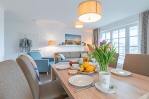 Ein Hotelzimmer mit Esstisch, gedecktem Tisch für das Frühstück, einer Couch, einer Lampe und Blick auf die Stadt.
