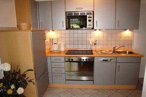Een kleine keuken met een magnetron, fornuis, oven en spoelbak.