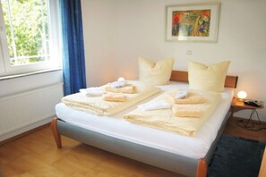 Ein Doppelbett mit zwei Kissen, ein Nachttisch mit Lampe und ein Bild an der Wand.