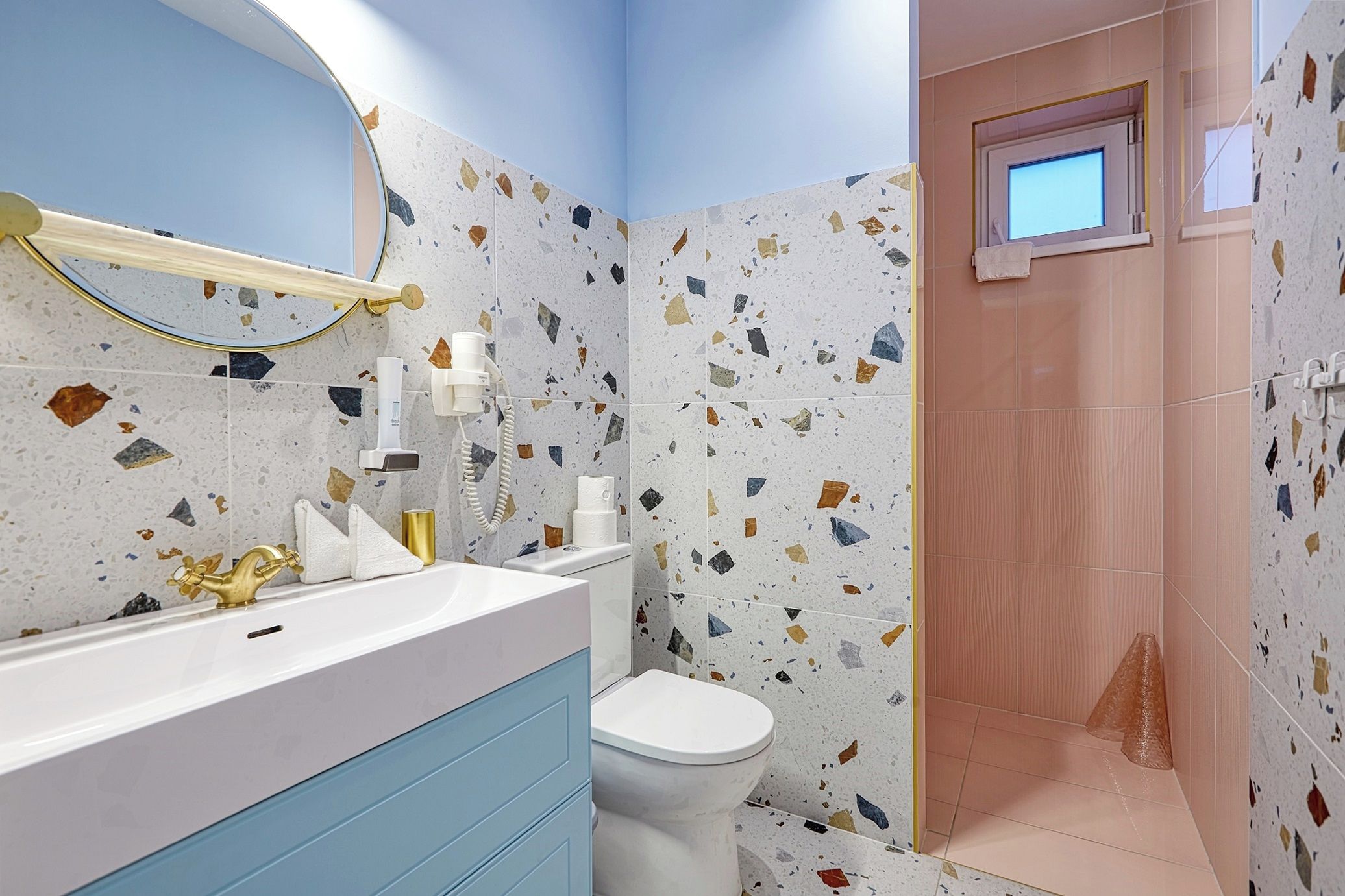 Ein Badezimmer mit einem weißen Waschbecken, einem goldenen Wasserhahn und einem blauen Schrank.