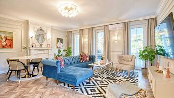 Amplia sala de estar con un sofá seccional azul, un tapete estampado y una zona de comedor con mesa y sillas.
