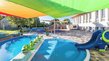 En swimmingpool med vattenrutschkanor och en lekplats för barn.