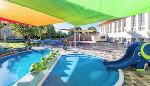 A swimming pool with slides and a children's play area.