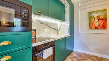 Una cocina con armarios verde azulado, encimera de mármol y un cuadro en la pared.