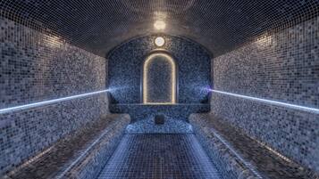 Une structure en forme de tunnel, dotée d’un plafond et de murs ornés de motifs, d’une arche centrale illuminée et d’un sol à motifs géométriques.