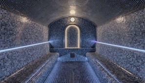 Une structure en forme de tunnel, dotée d’un plafond et de murs ornés de motifs, d’une arche centrale illuminée et d’un sol à motifs géométriques.