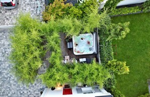 Luchtbeeld van een dakbostuin met een jacuzzi, omringd door weelderige begroeiing en een verhard pad.