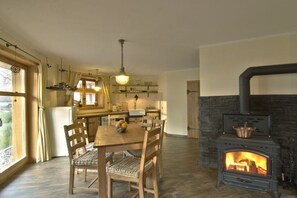 A cozy kitchen with a central island, a dining table with chairs, and a wood-burning stove. - Holiday home Amber seeker (Sellin)