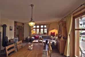 A cozy living room with a wooden dining table, a sofa, and a fireplace. - Holiday home Amber seeker (Sellin)