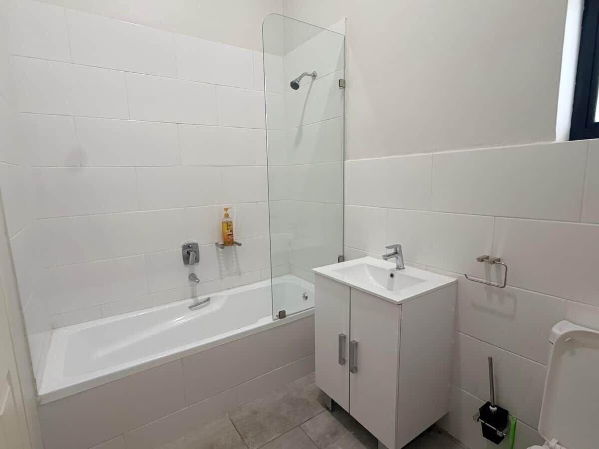 A bathroom with a bathtub, a sink, and a glass shower enclosure.