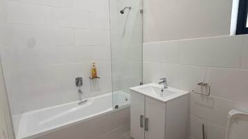 A bathroom with a bathtub, a sink, and a glass shower enclosure.