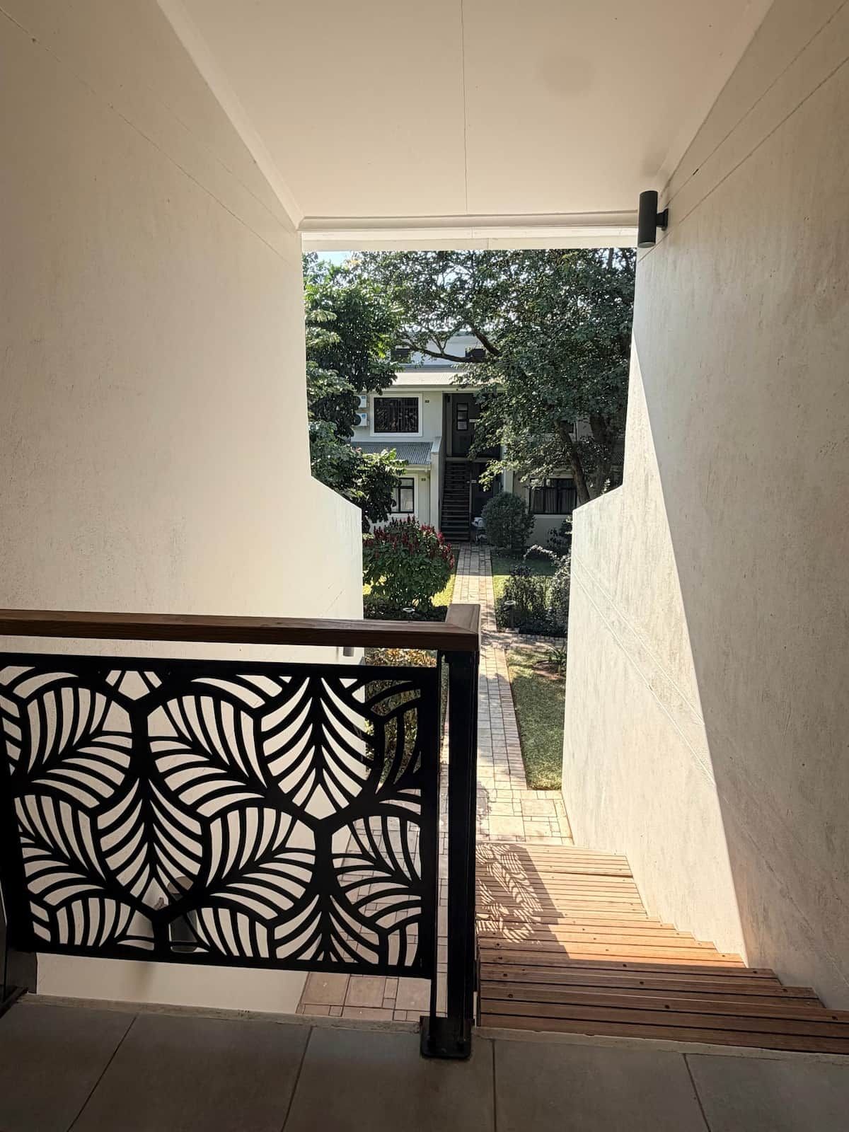 A staircase leading to a residential area with a view of a house and garden.