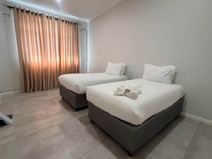 A hotel room with two beds, a large window with curtains, and a tiled floor. - Dreams Apartment 115 (Victoria Falls)