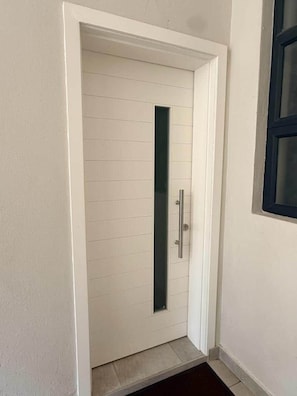 A white door with a vertical handle and a glass panel. - Dreams Apartment 115 (Victoria Falls)