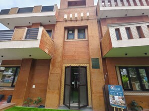 A multi-story building with a central entrance, large windows, and a signboard. - hotel roomin (Noida)