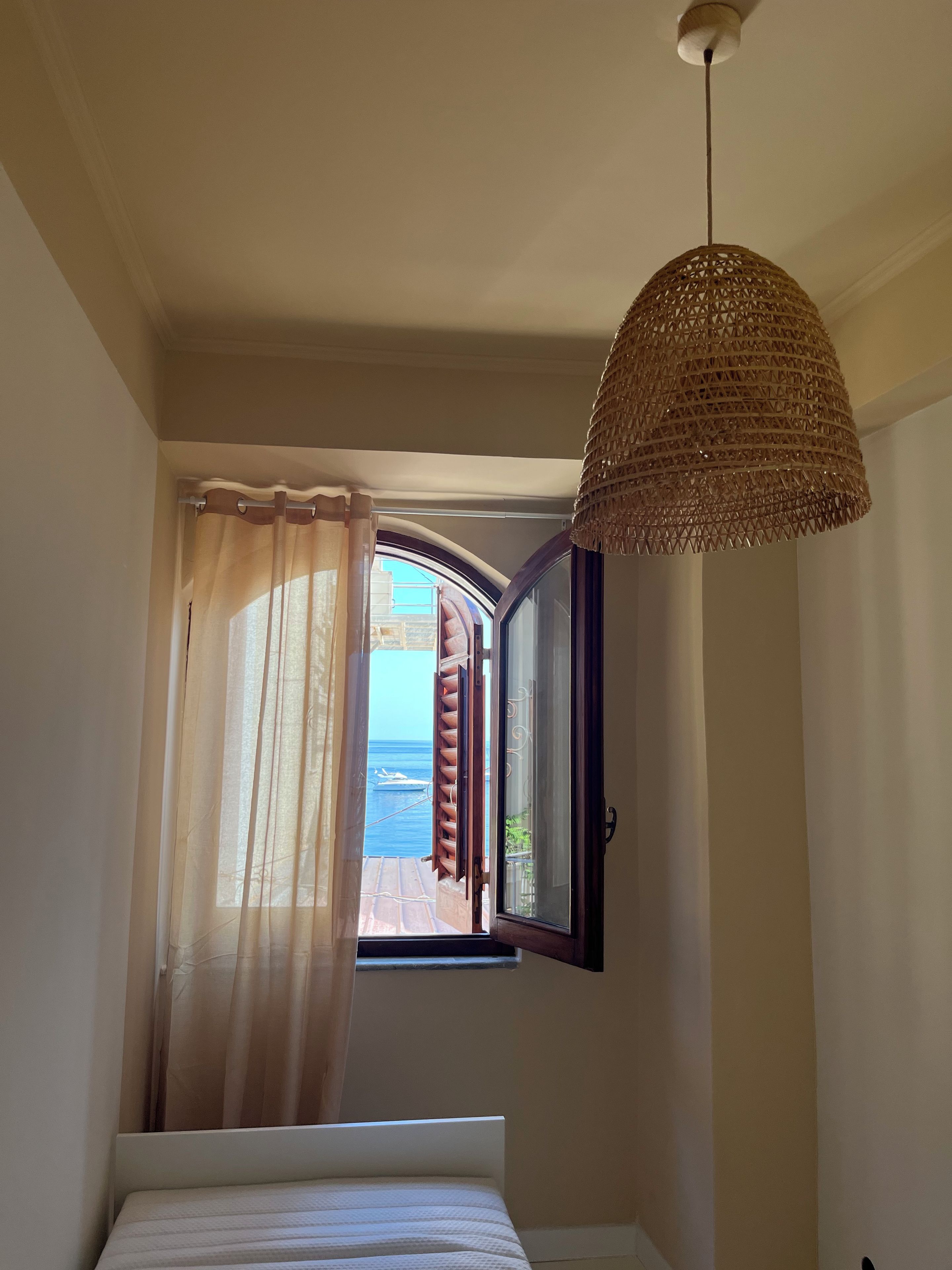 Una camera da letto con un letto, una finestra con tende e una lampada a sospensione.
