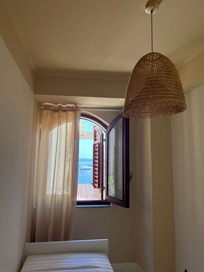 Ein Schlafzimmer mit einem Bett, einem Fenster mit Vorhängen und einer Hängelampe.