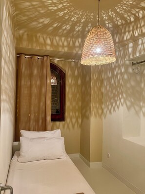 Ein Schlafzimmer mit einem Bett, einer Hängeleuchte, einem Fenster und einer Dusche.
