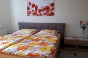 A bedroom with a bed, a nightstand, a vase with flowers, and a wall-mounted painting. - Fischerweg - Villa Angelika (Seebad Bansin)