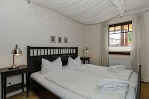 Ein Hotelzimmer mit einem großen Bett, zwei Nachttischen, einem Fenster mit Vorhängen und Blick nach draußen.