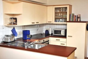 A kitchen with white cabinets, a microwave, a toaster, and a coffee maker. - Holiday home with 2 bedrooms (Kaltenhof (Insel Poel))