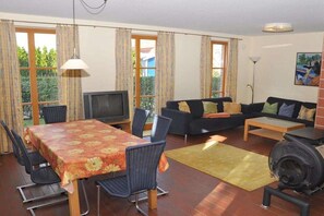 A furnished living room with a dining table, sofa, and a fireplace. - Holiday home with 2 bedrooms (Kaltenhof (Insel Poel))