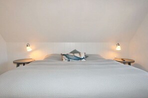 Ein Schlafzimmer mit einem großen Bett, zwei Nachttischen und Wandleuchten.