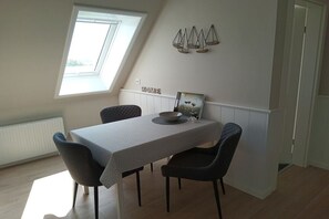 Ein Essbereich mit Tisch, Stühlen, einem Fenster und Wanddekoration.