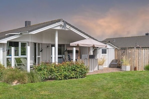 A single-story house with a covered patio, a fenced backyard, and a satellite dish. - Holiday home in the North Sea with 2 bedrooms (Wesselburenerkoog)