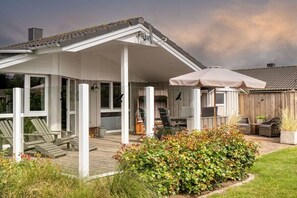 A house with a covered patio, outdoor seating, and a garden. - Holiday home in the North Sea with 2 bedrooms (Wesselburenerkoog)