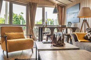 A cozy living area with a sofa, armchair, and coffee table, featuring a view through large windows. - Holiday home in the North Sea with 2 bedrooms (Wesselburenerkoog)