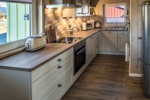 A modern kitchen with a wood floor, built-in appliances, and a window providing natural light. - Holiday home in the North Sea with 2 bedrooms (Wesselburenerkoog)