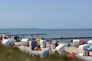 Ein Strand mit Strandkörben und Menschen, die im Wasser schwimmen.