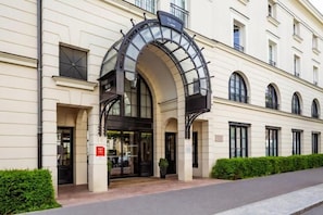 A hotel entrance with a large arched glass canopy, a double door, and a sign indicating a public area. - Disneyland Deluxe flat (Serris)