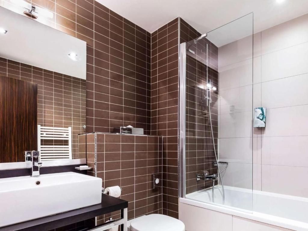 A modern bathroom with a glass-enclosed shower, a white sink, and a toilet.