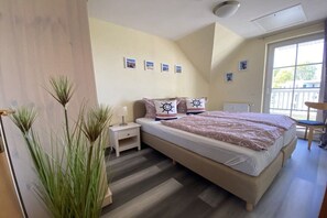 A bedroom with a bed, bedside tables, a window, and a view of the outside. - Harbor idyll holiday apartment steering wheel (Karlshagen)