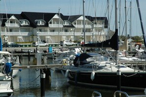A marina with boats docked, a building with balconies, and a clear sky. - Harbor idyll holiday apartment steering wheel (Karlshagen)