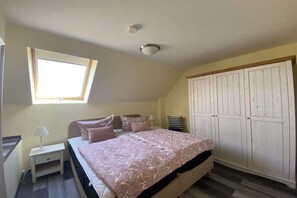 Un dormitorio con una cama, una mesita de noche, un ventanal y un armario.