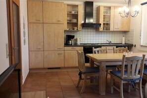 A kitchen with wooden cabinets, a stove, and a dining table with chairs. - Holiday home with 1 bedroom (Poel \/ OT Kaltenhof)