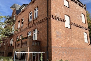 Ein Gebäude aus roten Ziegeln mit vielen Fenstern und einem Balkon.