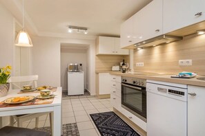 A modern kitchen with white cabinets, a built-in oven, and a dishwasher. - Holiday apartment in Binz with swimming pool (Binz)