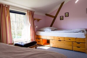 A bedroom with a single bed, a bench, a window with curtains, and a sloped ceiling. - Holiday apartment with 2 bedrooms (Westerholz)
