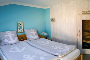 Une chambre à coucher avec un lit, une table de chevet, une lampe et une porte en bois sur laquelle est apposée une pancarte.