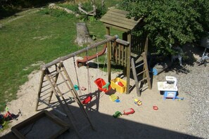 A playground with a wooden slide, climbing ladder, and various toys scattered on the ground. - Holiday apartment with 2 bedrooms (Westerholz)
