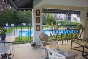 A covered outdoor area with a pool, seating, and potted plants.