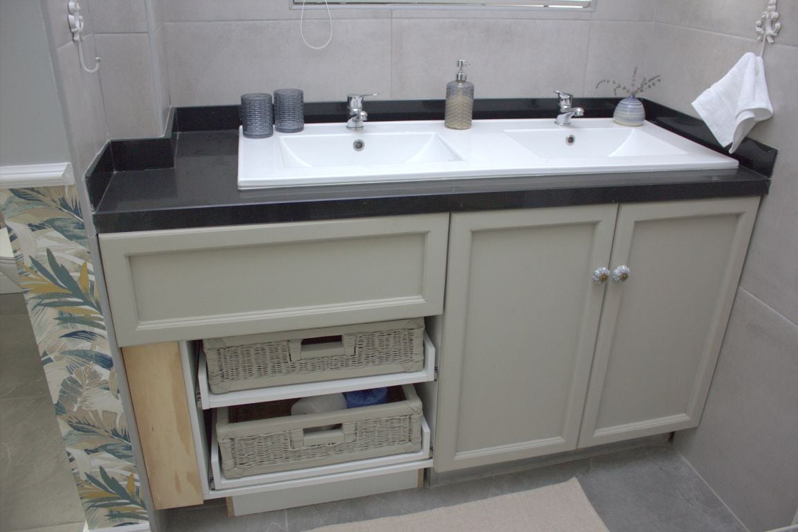 A bathroom with a double sink, two drawers, and a towel rack.